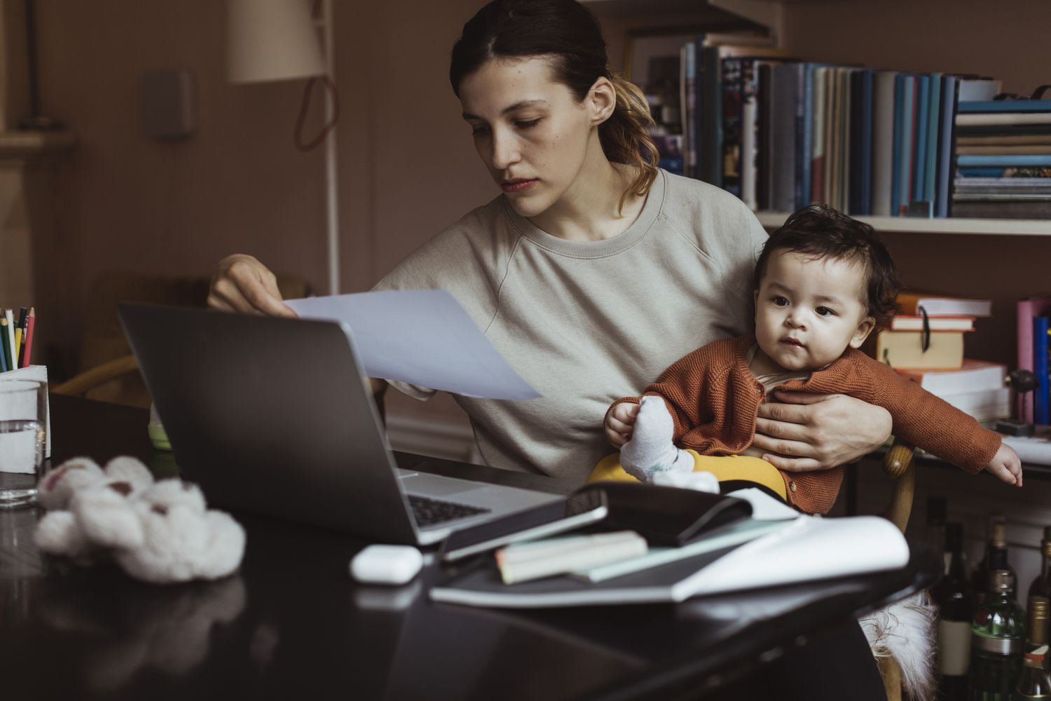 Woman doing bills with toddler on her lap