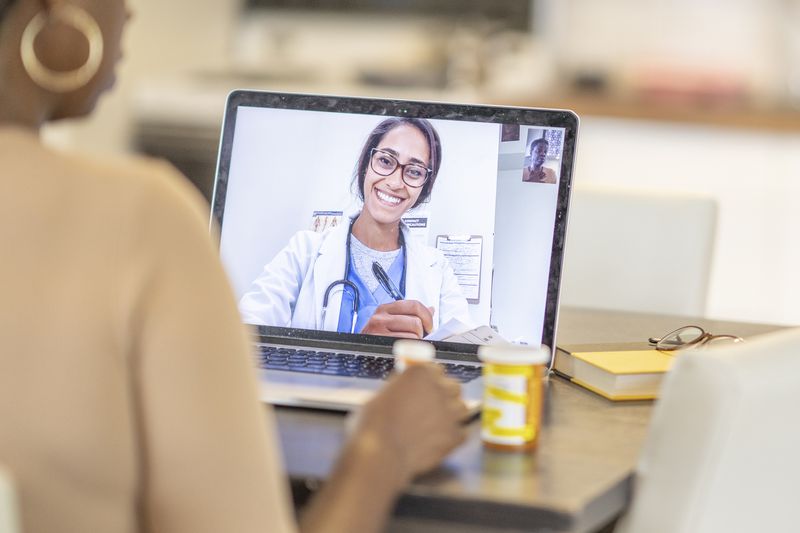 A woman meets with her healthcare provider via her laptop.