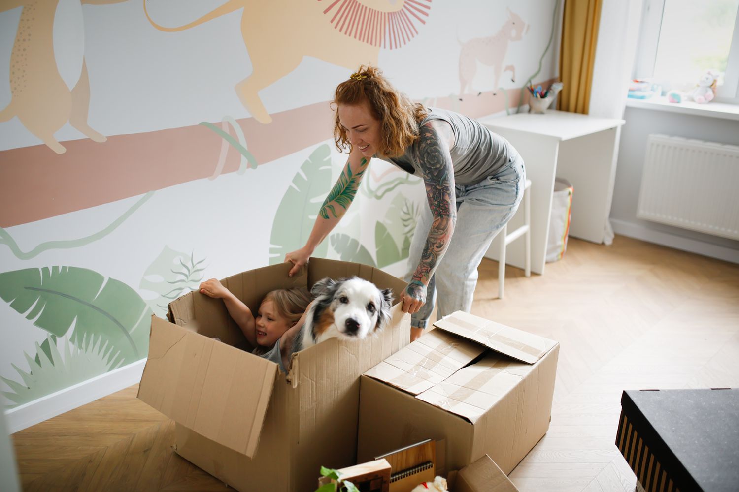 A woman pushes a cardboard box with a child and a dog on moving day