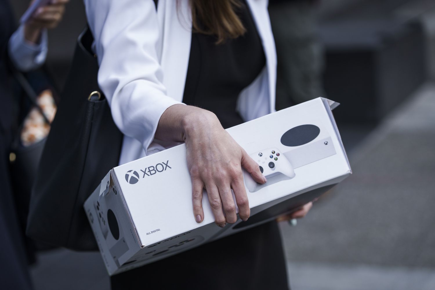 An attorney with the Federal Trade Commission (FTC) carries an XBOX game console box.