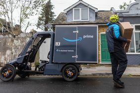 An employee delivers a parcel from an Amazon.com Inc. electric cargo delivery bike in Croydon, UK, 