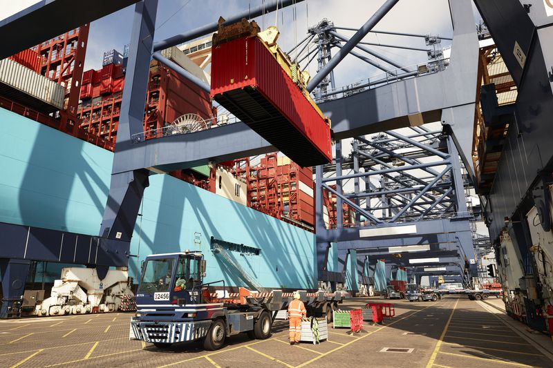 Crane lowering cargo container onto truck at a port.