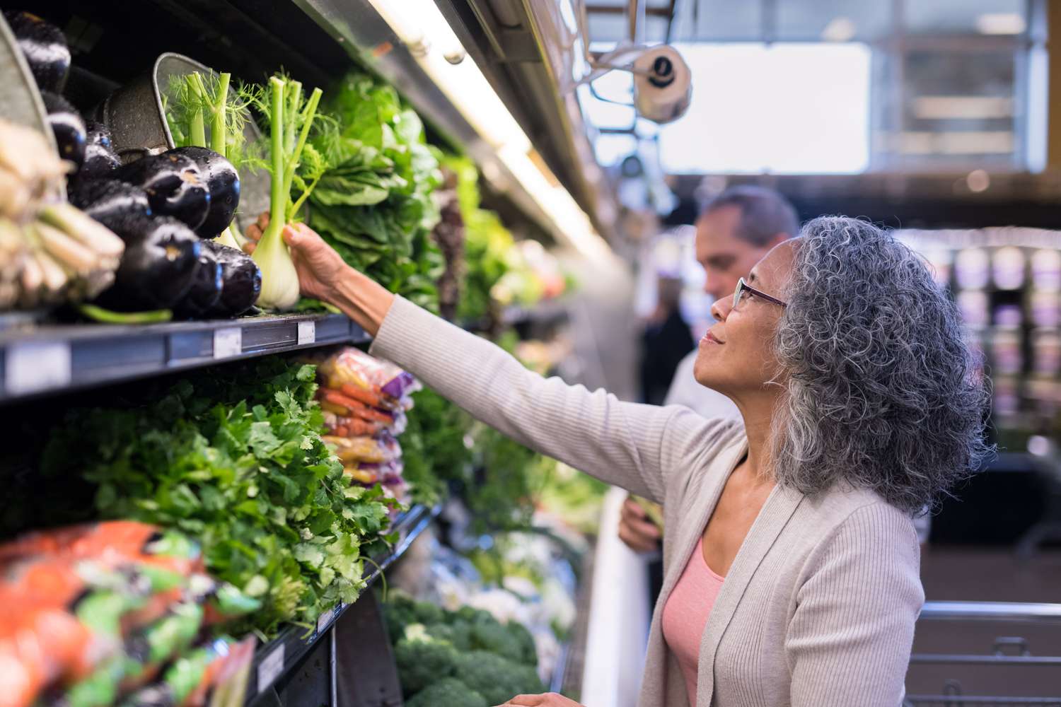 A senior woman picks out fresh produce together at the supermarket. 