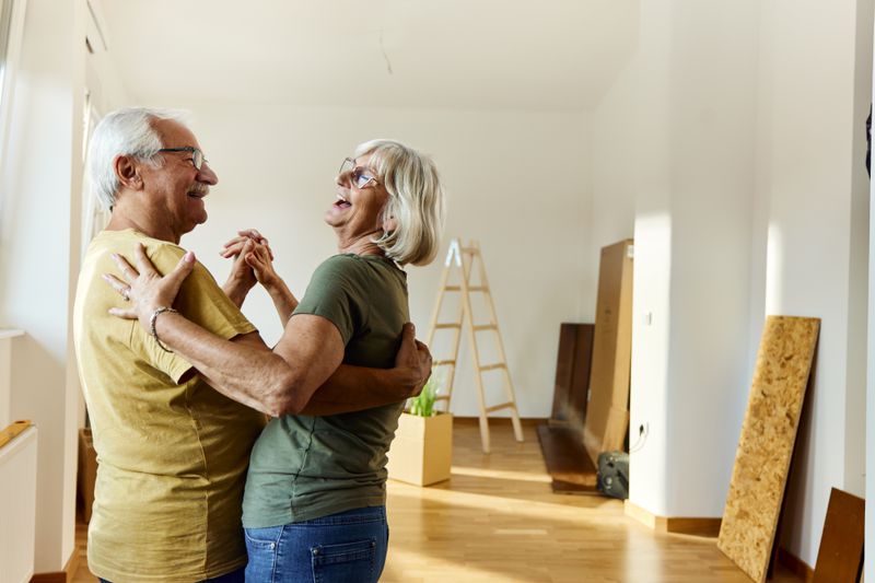 Senior couple dancing happily in their new home after changing their Medicare coverage successfully through special enrollment period due to moving.