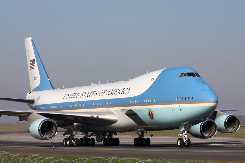 A large aircraft with "United States of America" written on its side, identified as Air Force One, on a runway