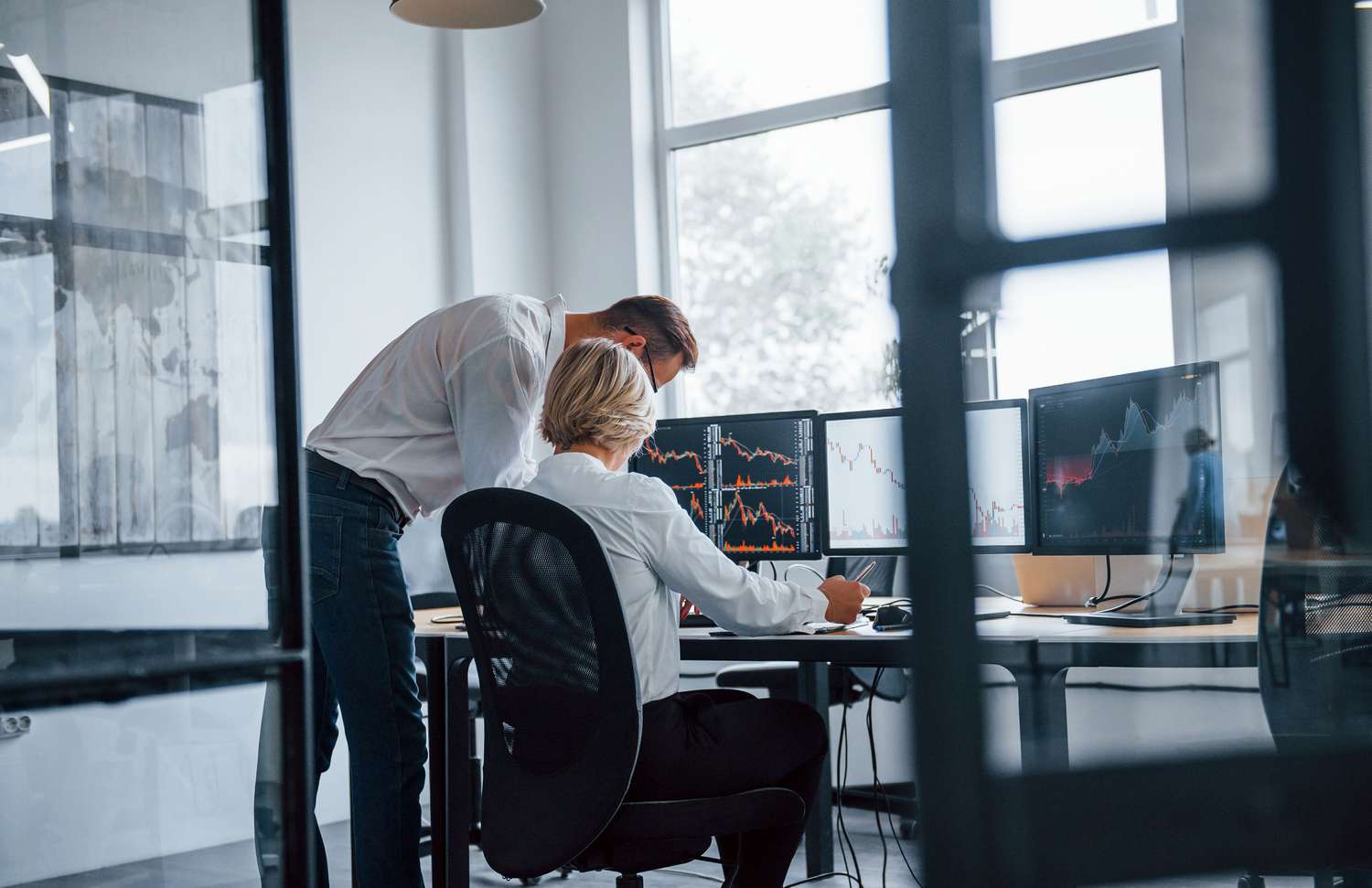 Two people reviewing information at a computer in an office