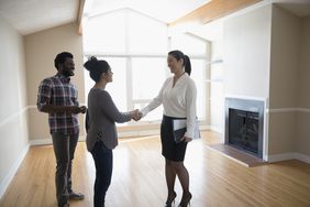 Young couple buying new house, shaking hands with real estate agent in agreement