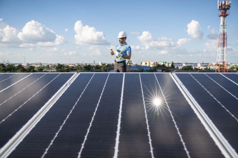 A solar farm worker uses a digital tablet to measure the fluctuation in the output of an array of solar panels.