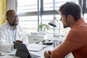 Male doctor discussing with patient in clinic about Health Insurance