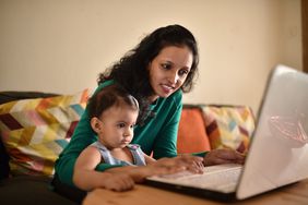 Woman shopping online with her toddler baby in the lap.