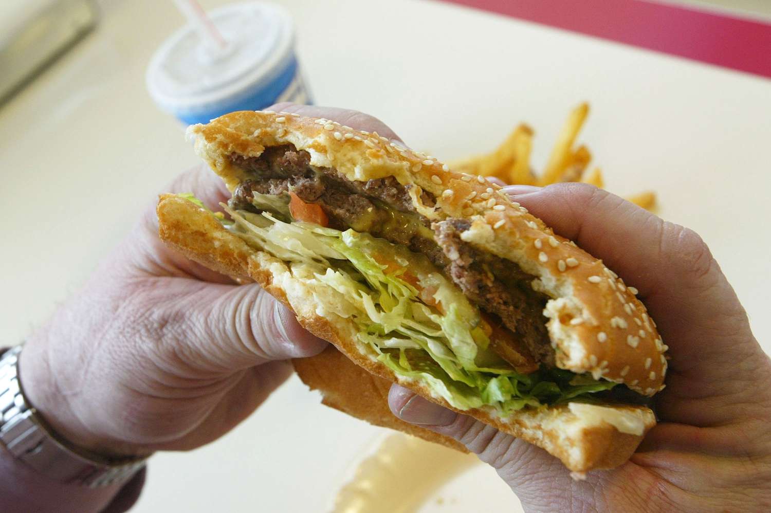 A person holding a hamburger with bites already taken out of it.