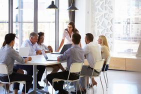 The eight stockholders of a small public company meet around a table to discuss business strategy and review earning results. 