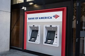 The Bank of America logo is seen above two ATMs on the street.