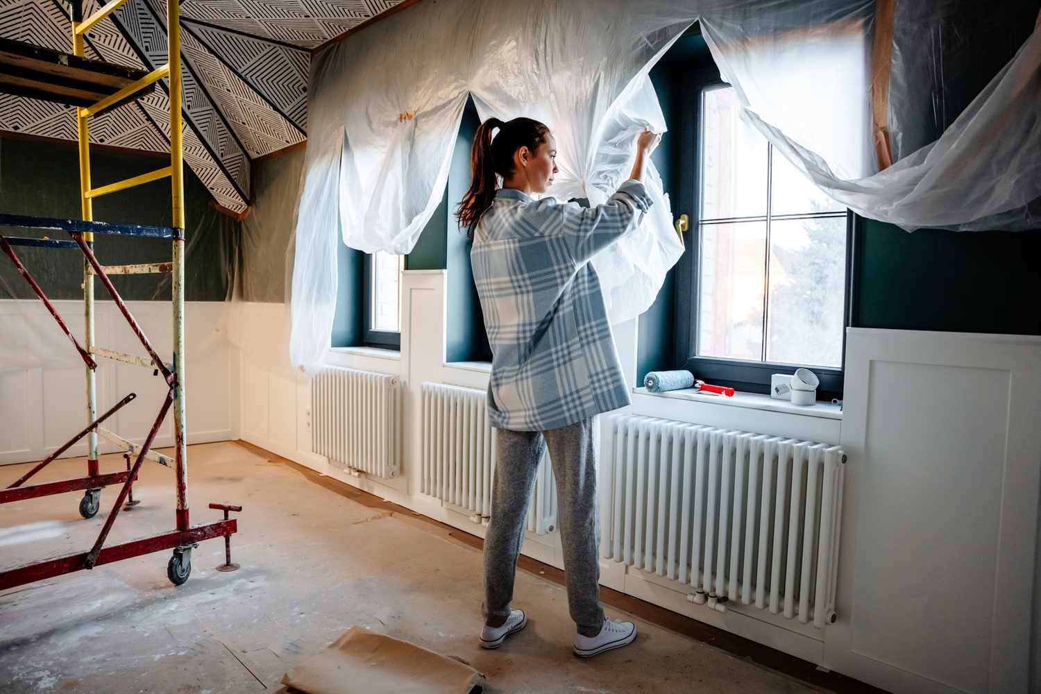 A woman is engaged in home improvement, removes protective polyethylene after repair.