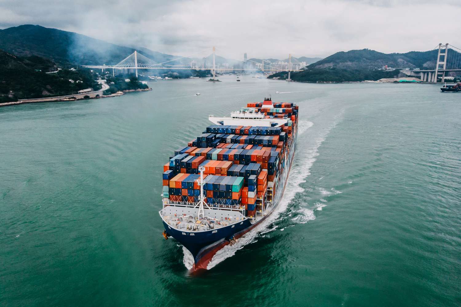 Aerial view of container ship transporting goods sailing across ocean leaving the port