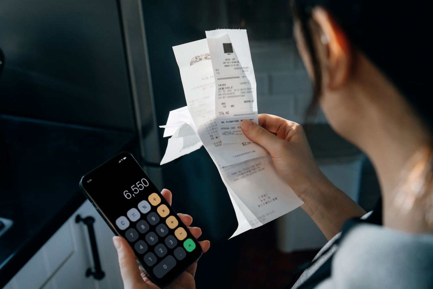 Woman calculating financial bills and receipts over kitchen counter, managing personal banking and finance