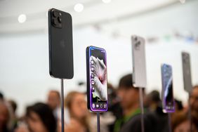 Five iPhone 16s are on display in front of a crowd of people.
