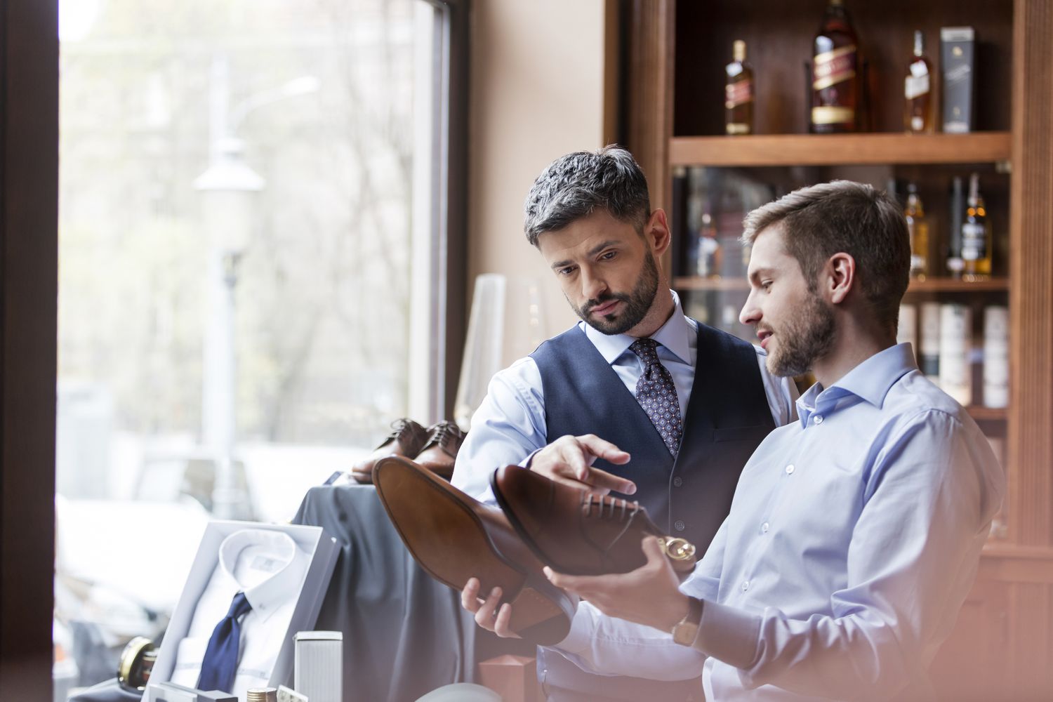 Businessmen examining dress shoes in menswear shop
