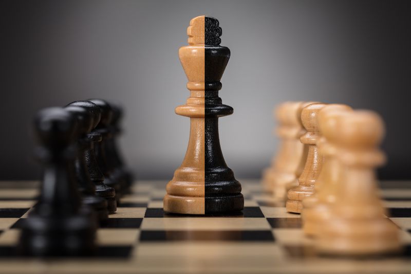 Black- and brown-colored king and pawns on chess board.