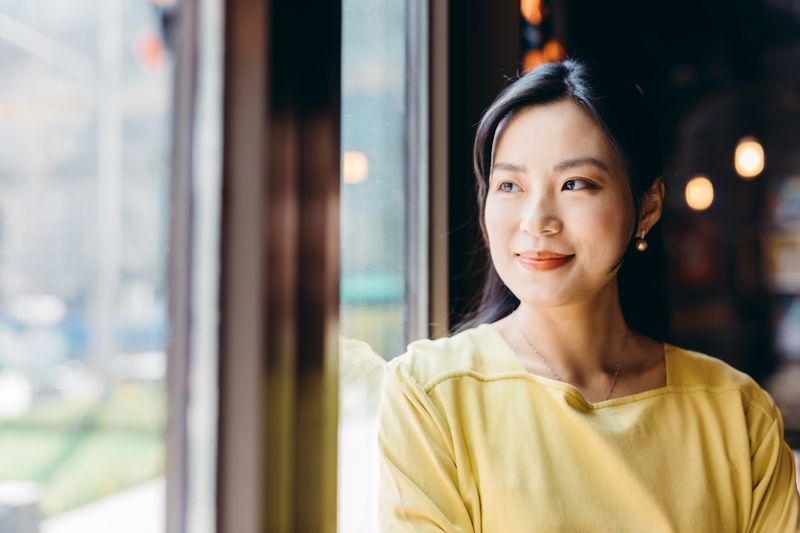Woman looking out of a window and reflecting on her goals