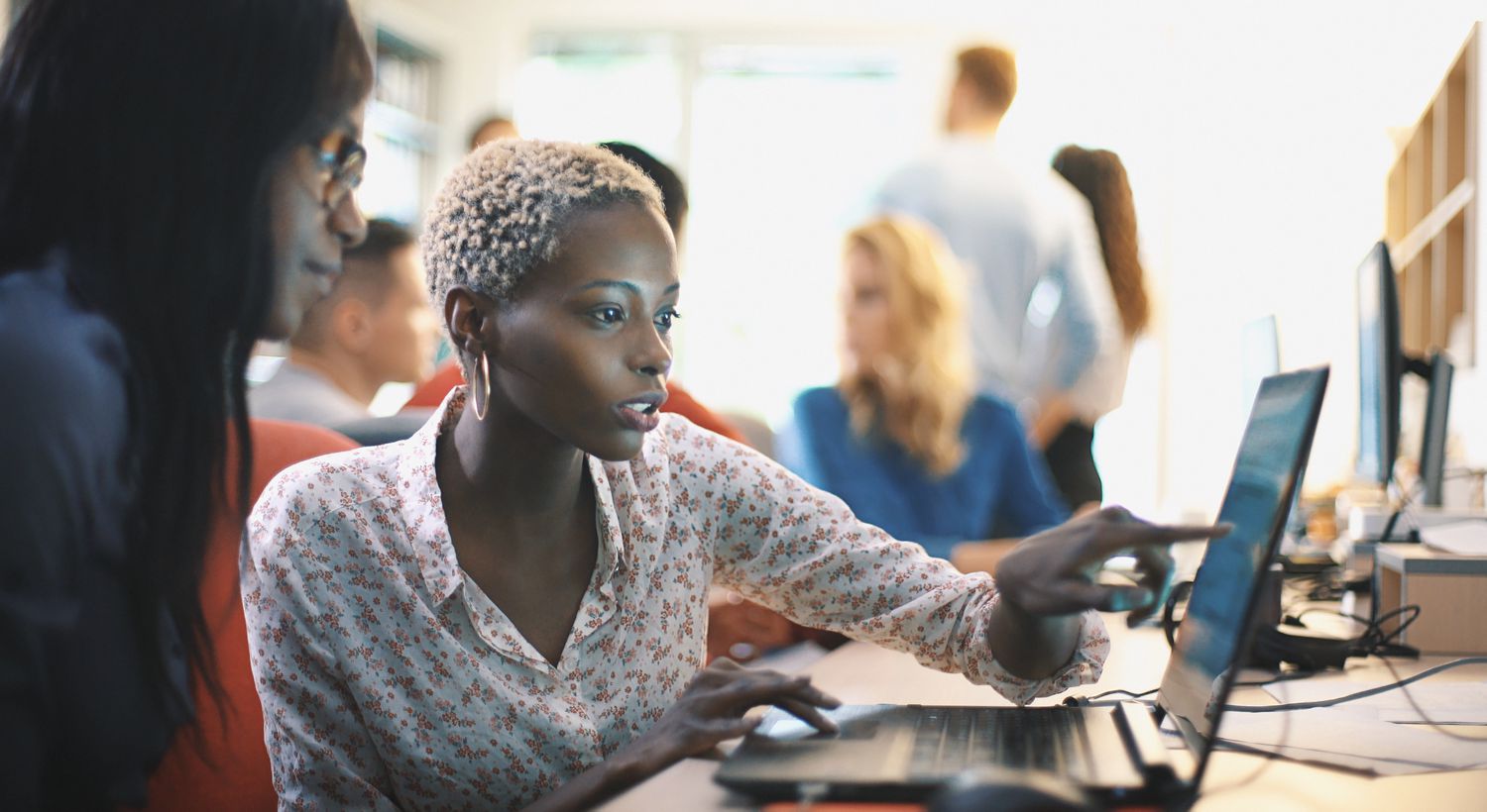 Two women discussing a project while looking at a laptop