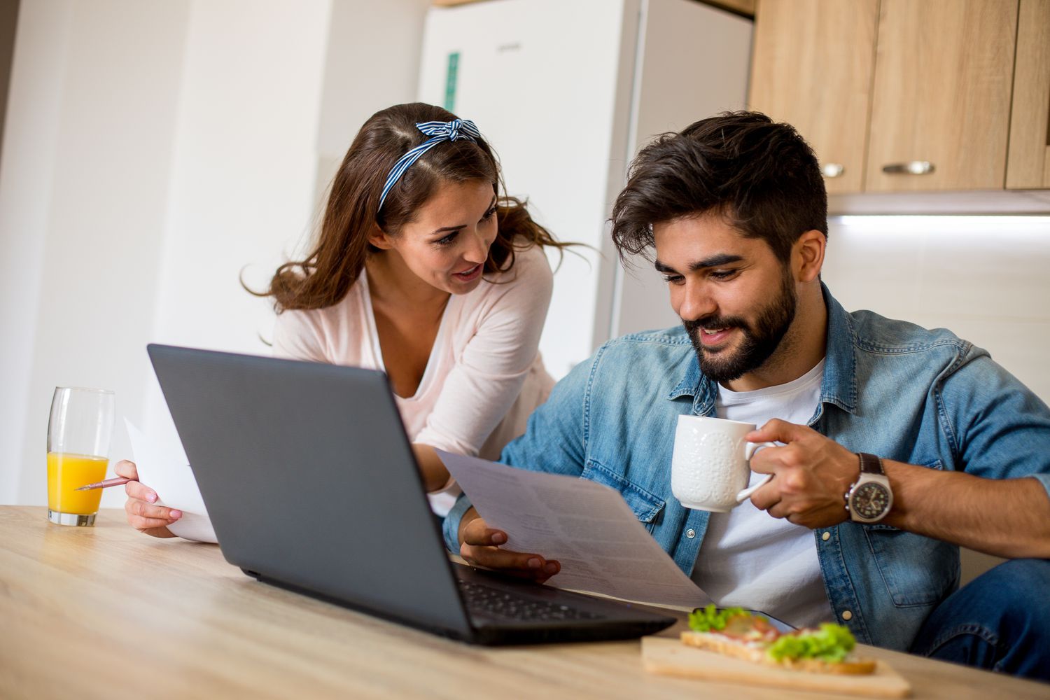 Happy couple in the kitchen at home reading a document informing a principal reduction on their mortgage.