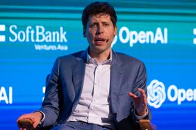 Sam Altman CEO of OpenAI, sitting on a podium with OpenAI sign behind him