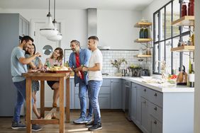 Friends enjoying a meal in the kitchen of a home.