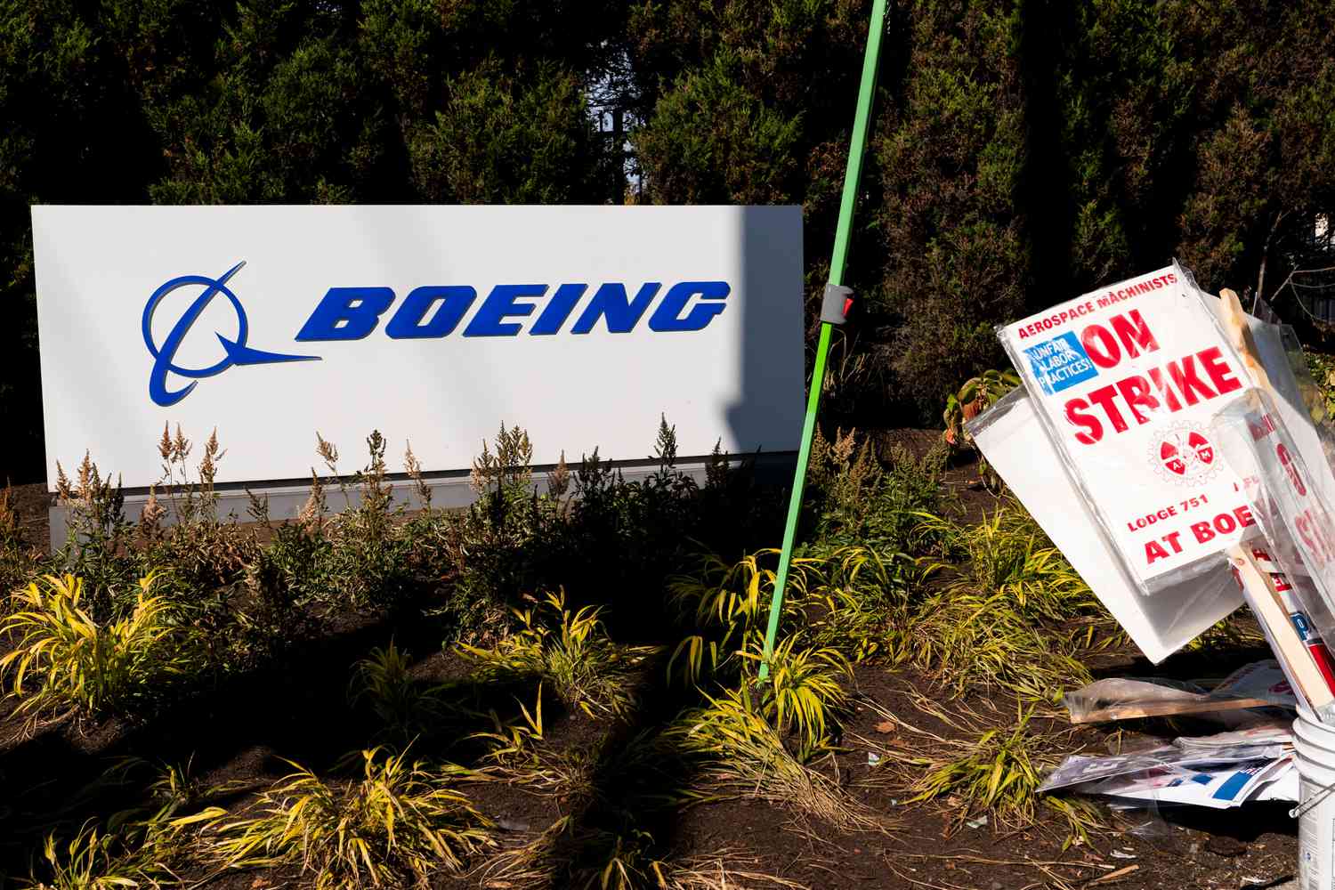 A pile of strike picket signs sit next to a Boeing sign