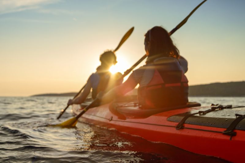 Rear view of male and female kayakers paddling in sea.