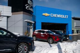 Cars are parked outside a Chevrolet and Cadillac car dealership with snow on the ground.
