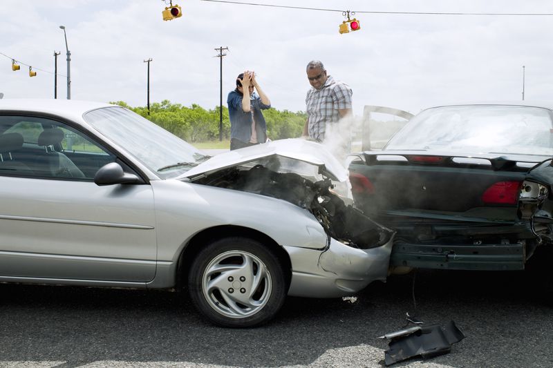 Two cars in an accident with drivers looking at damage