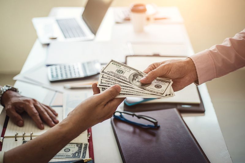 Hand of Business Man Giving Money for Taking Bribe While Making Contract
