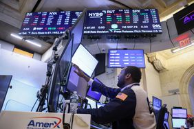 A stock trader working at a computer station, stock market data displayed on screens above