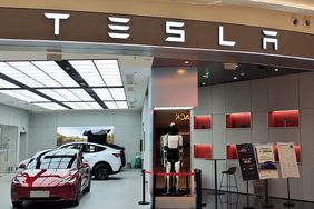 Cars, an Optimus robot, and the Tesla logo are seen in a Tesla storefront in China.