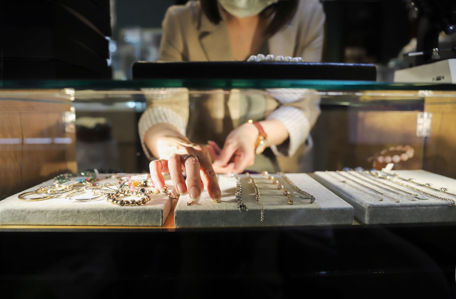 A stock image of a jewelry-store worker and a case of products on a counter. 