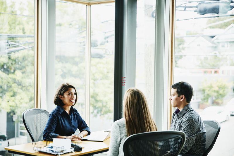 financial advisor in discussion with clients at office workstation
