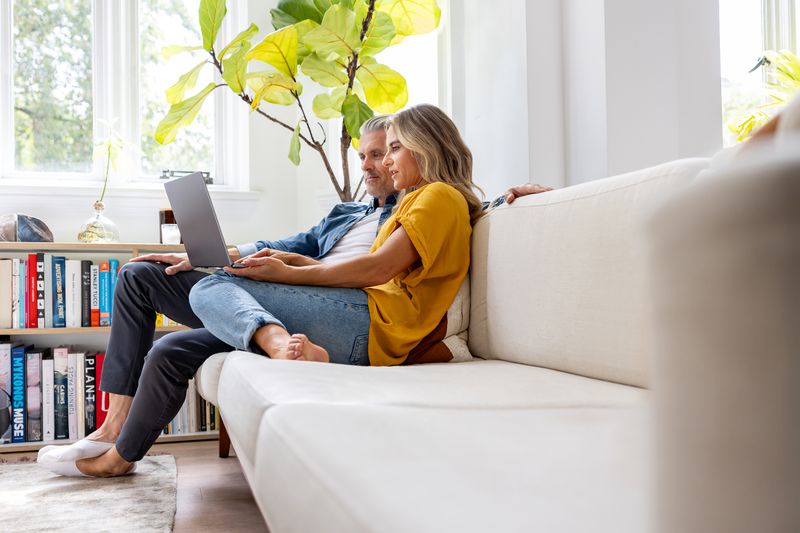 Couple using laptop on couch