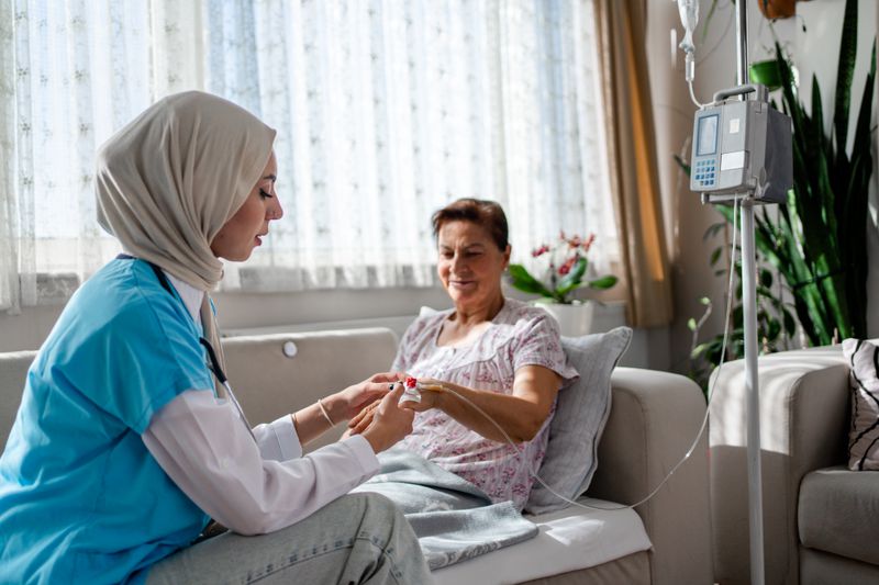 Female healthcare worker in a headscarf visiting female patient at home