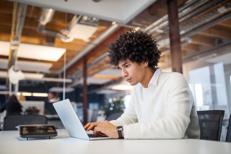 Young man at a laptop in an office at a conference table