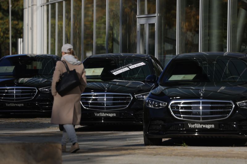 A woman walks past Mercedes-Benz cars on display at a Mercedes-Benz dealership