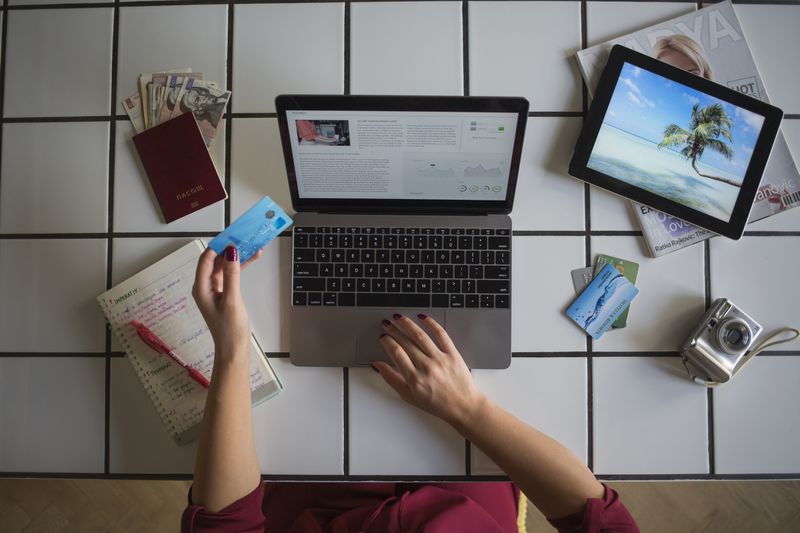A Young woman using laptop, paying with credit card.