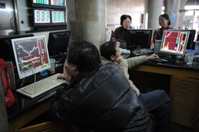 Traders looking at technical charts on computers in an office.