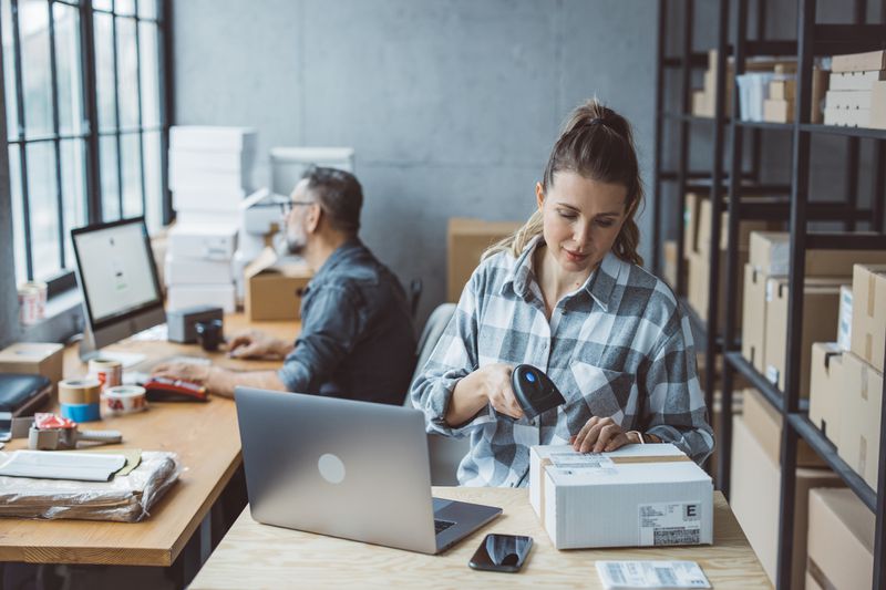 Two Small-Business Owners Working on Computers and Packing Merchandise