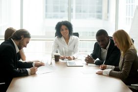 Businessman and businesswoman signing contracts with intermediary in between the two groups