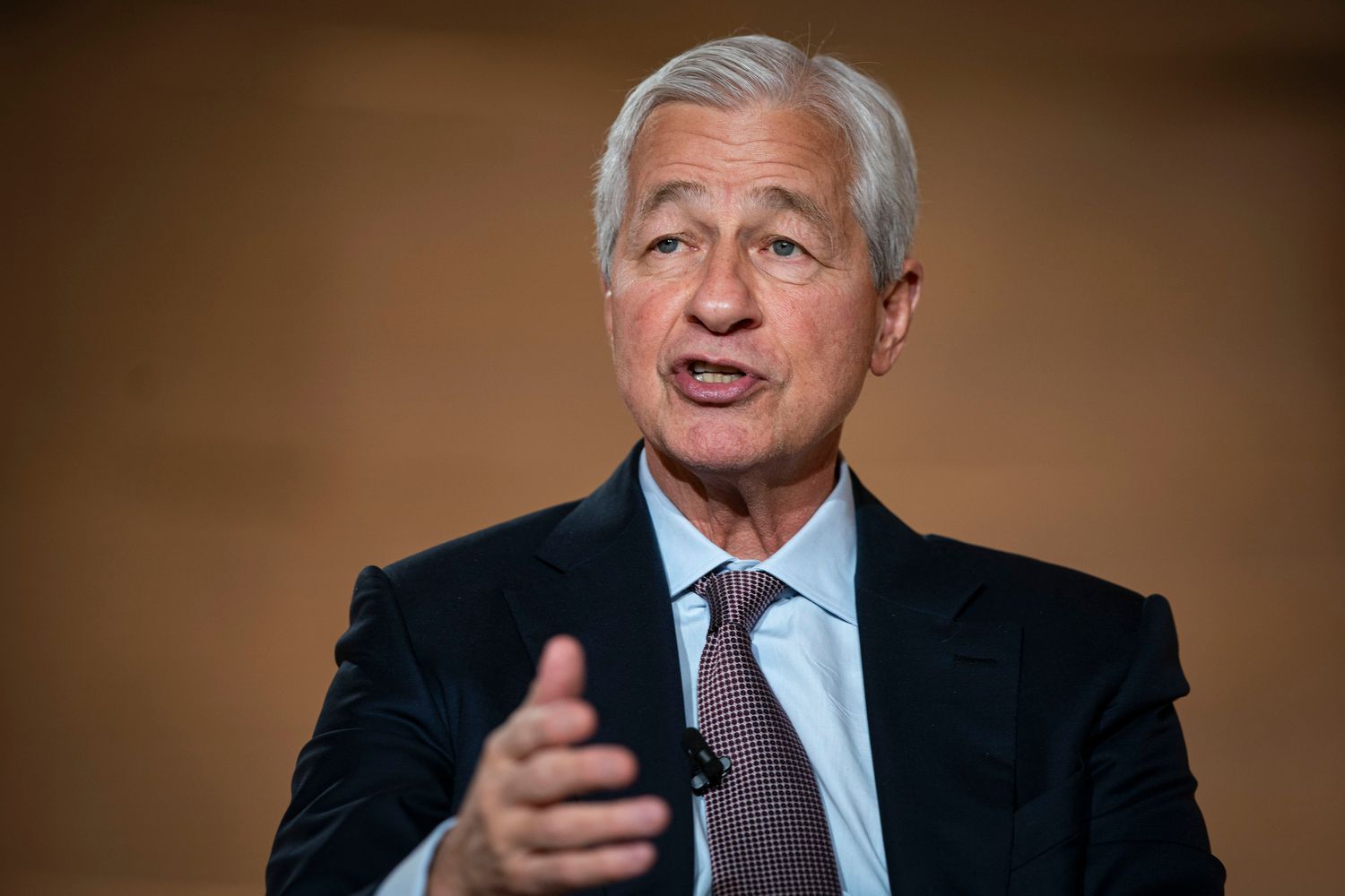 Jamie Dimon speaks while sitting in a black suit.
