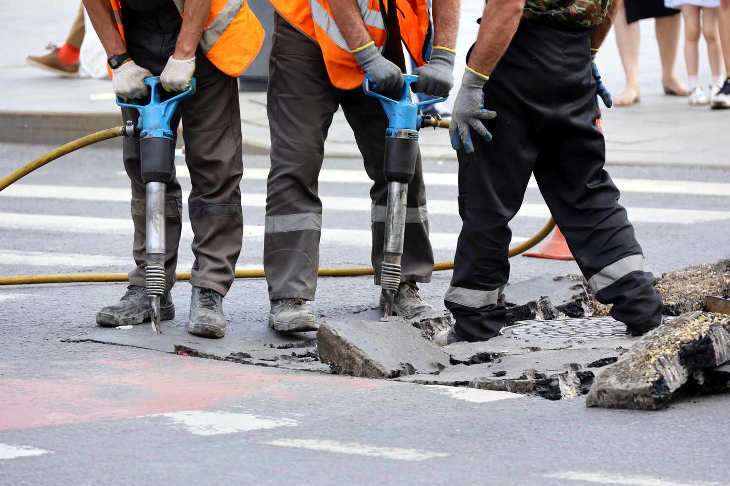 City workers use jackhammers to remove the road surface for an infrastructure-related repair of the storm sewer.
