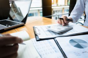 Financial graphs, and a person's hand using a calculator
