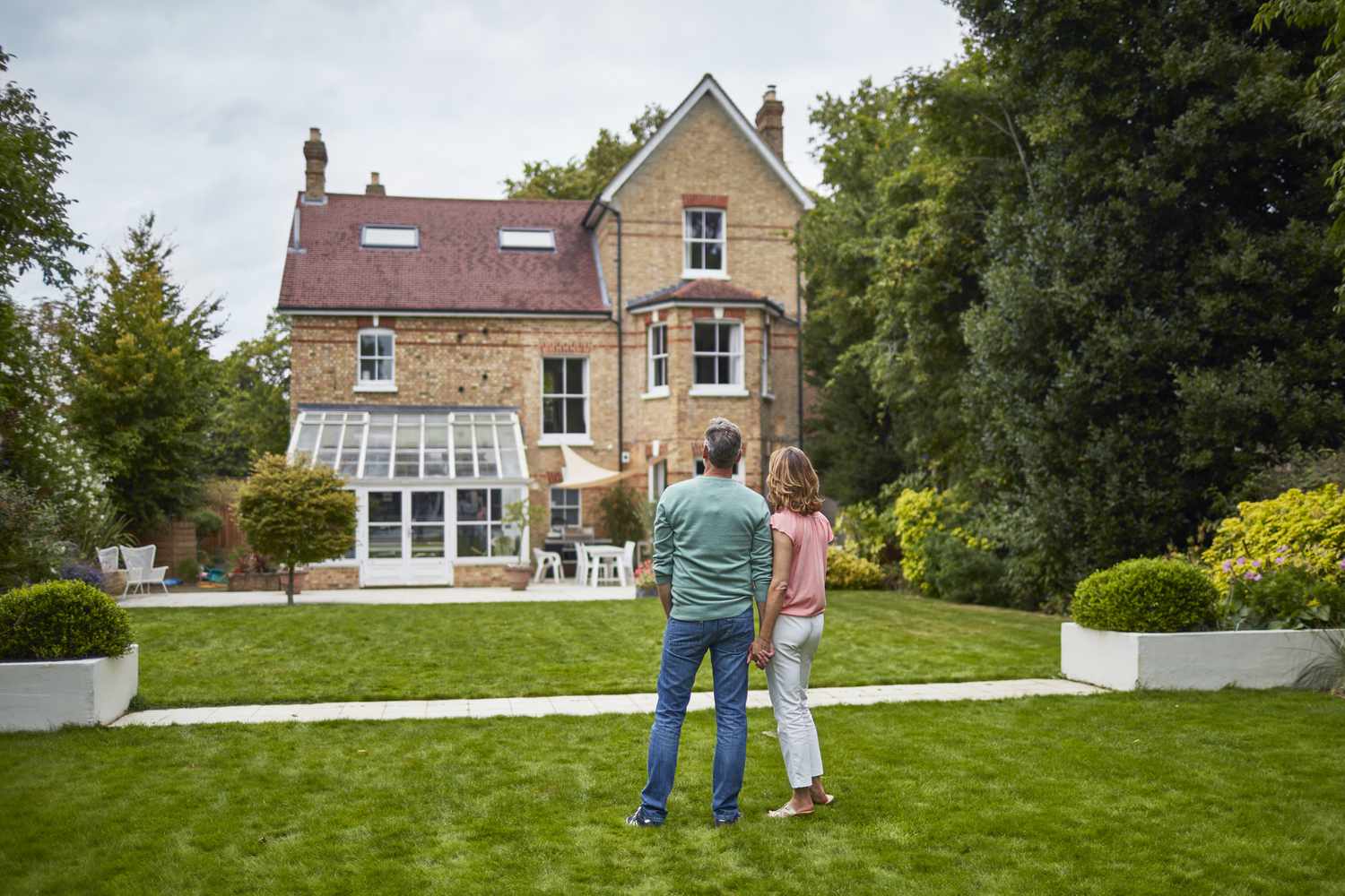Couple looks at house with their backs to the camera