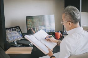 Man working at home with computer monitor monitoring stock market trends